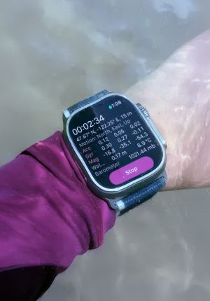 Underwater close-up of a person's wrist wearing a smartwatch displaying dive metrics.