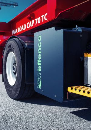 Close-up of a red terminal tractor's rear wheel with a black Effenco electrification module mounted beside it.