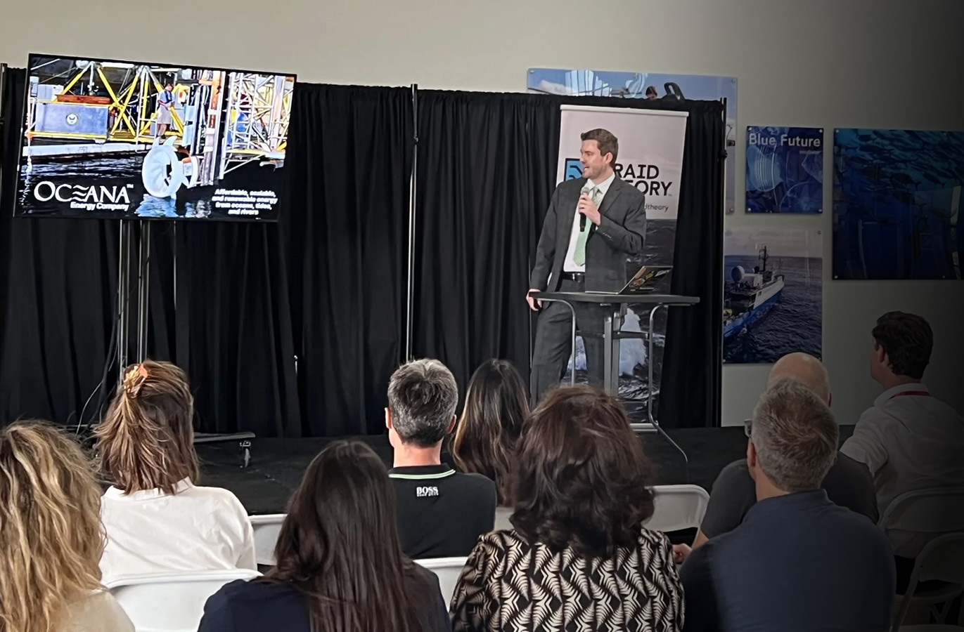 a man speaking in front of a seated crowd