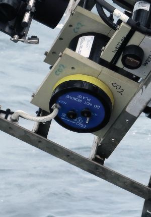Close-up of a CO2 sensor module mounted in a metal instrument frame above the sea.